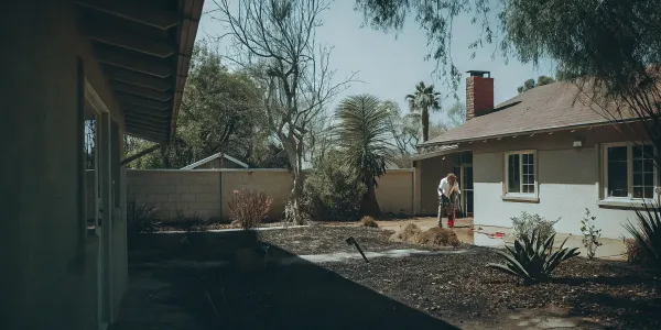 Homeowner clearing their yard following a home ignition zone checklist for wildfire protection.